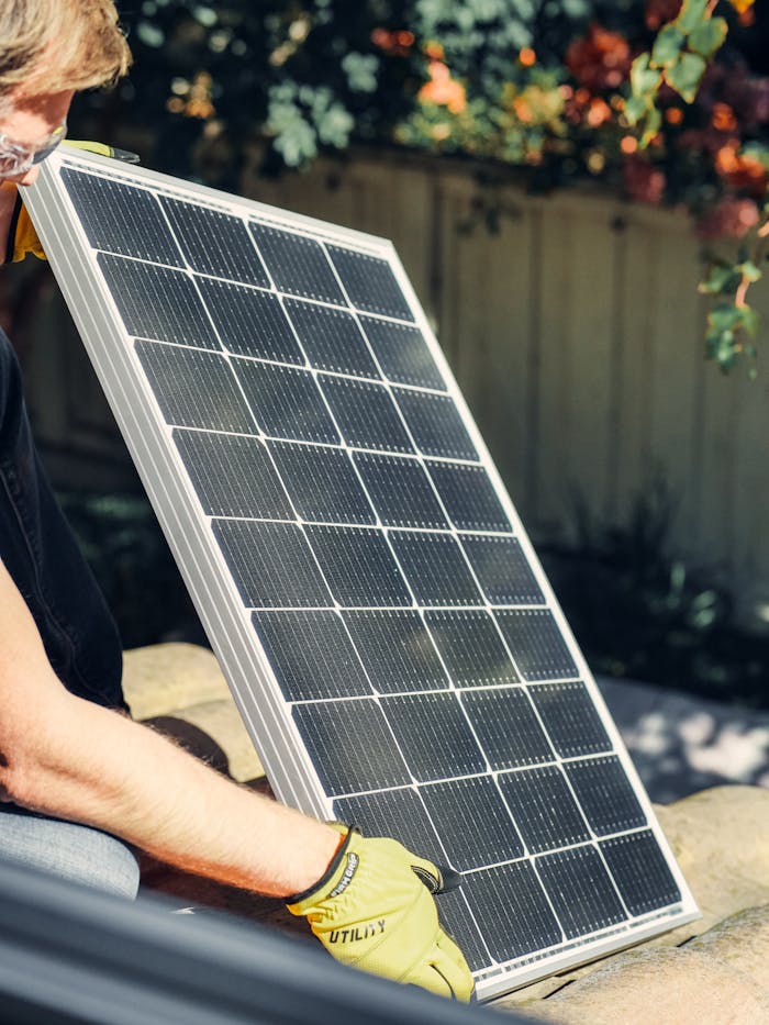 pexels-photo-9875410 A worker installs a solar panel in a garden, promoting clean energy.